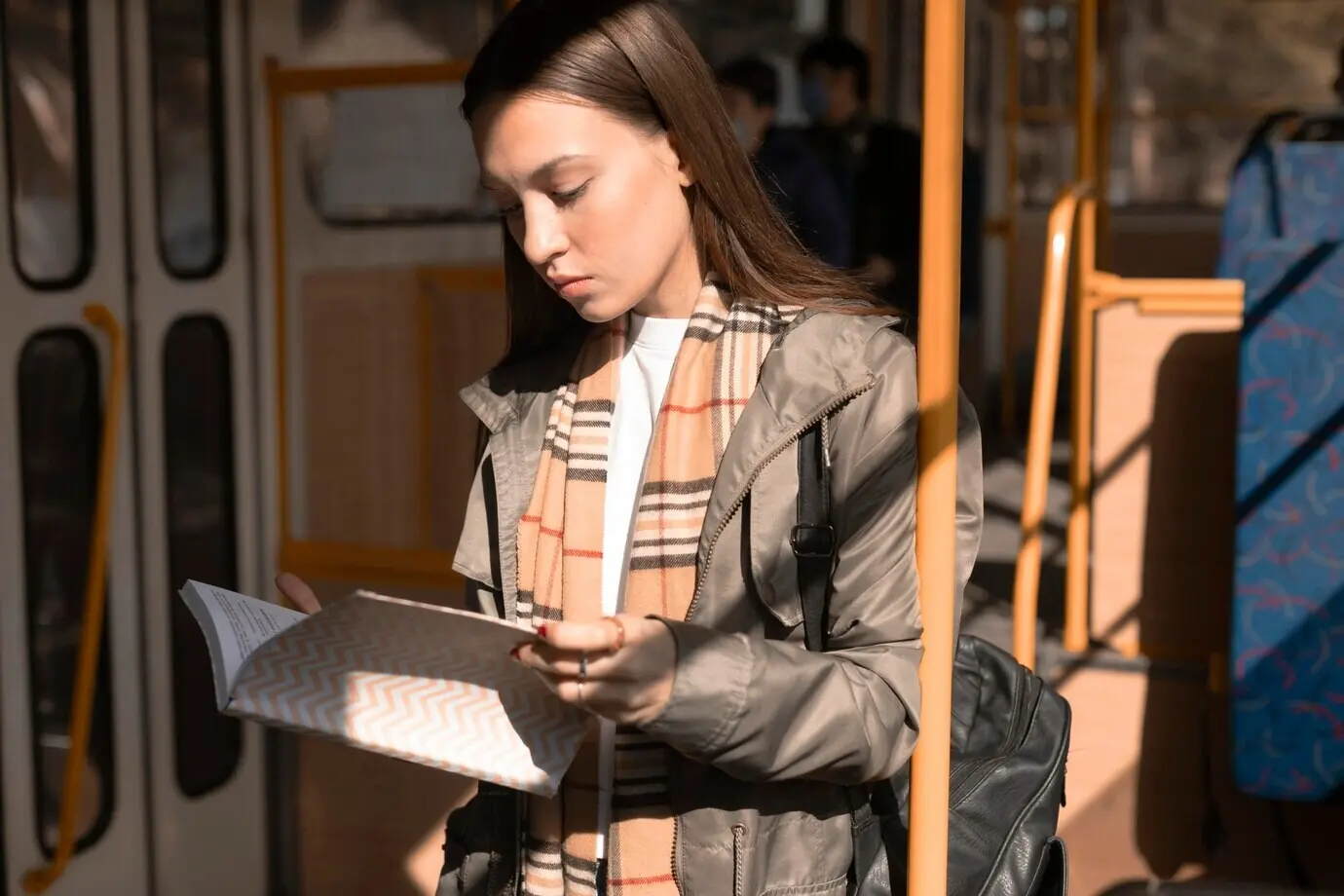 Eine Fahrgästin liest, während sie mit der Straßenbahn unterwegs ist.